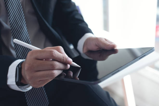 istock Businessman using stylus pen signing on e-document on digital tablet via mobile app at modern office, close up. E-signing, electronic signature concept 2181094782