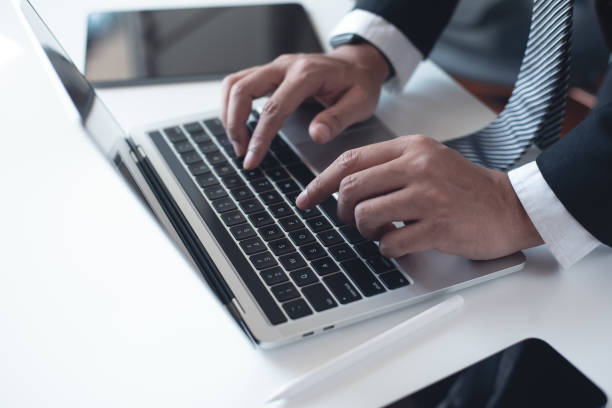 istock Businessman working on laptop computer on white table at office. Business man hands typing on laptop, online working, surfing the internet, close up 2181094988