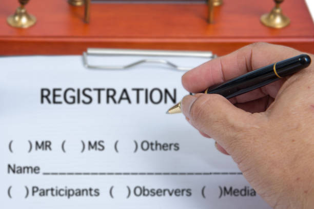 Close up picture of a person's hand is holding a pen to fill in the event registration information.
