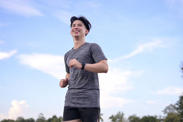 istock Happy smiling man jogging through a park during the late afternoon 2181100387
