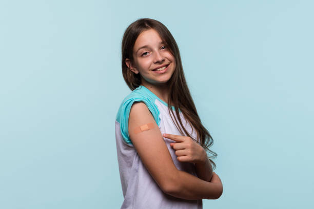 istock Girl smiles while pointing to bandage on arm 2181105137