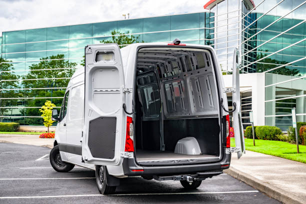 Light duty white cargo mini van make delivery to the business place and standing with open rear doors on the marked parking lot stock photo