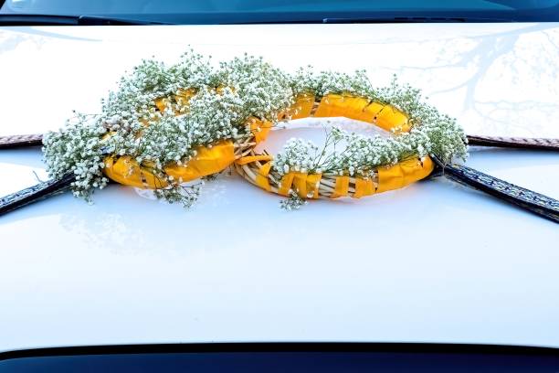 Wedding decorations on the hood of a white car.