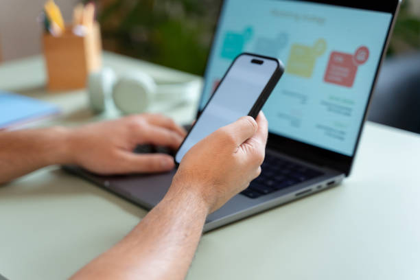 istock Businessman holding smartphone with laptop showing statistics on screen 2181117880