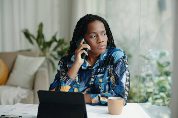 istock Contemplating Woman Speaking on Phone by Window 2181125478