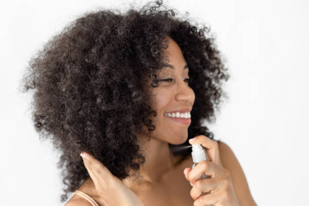 istock Pretty afro haired female spraying hairspray 2181126252