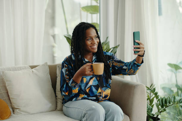 istock Smiling Woman Taking Selfie While Holding Coffee Cup 2181126383