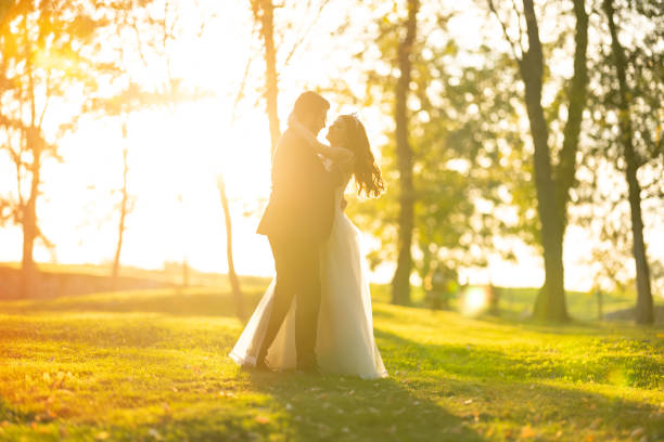 Full length shot of beautiful bride and groom dancing in park on sunny autumn day