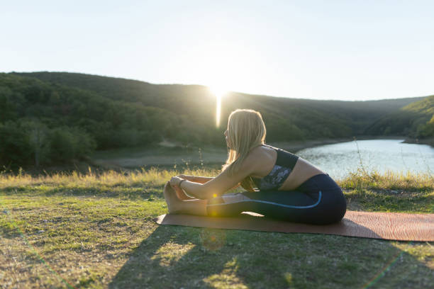 istock Attractive woman in seated forward bend pose. Sunset time 2181133280