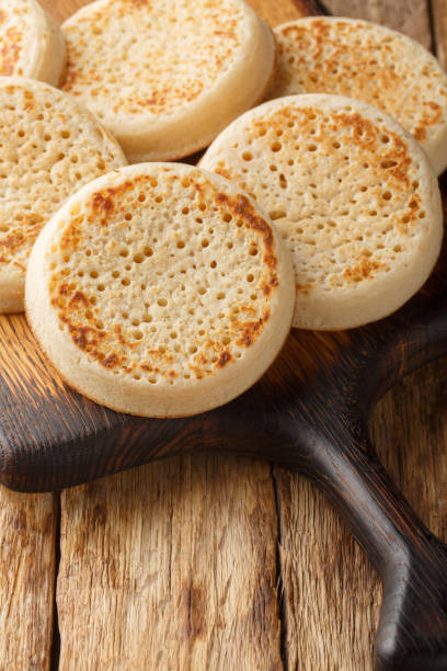 istock Crumpets fresh from a bakery closeup on the wooden board. Vertical 2181133692