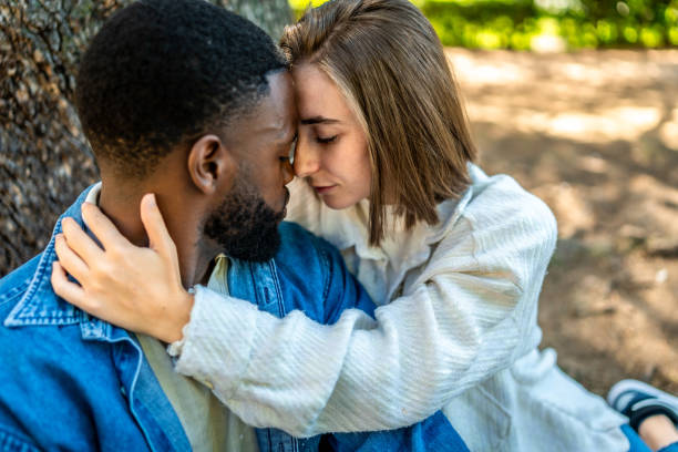 istock Romantic multiracial couple embraced sitting on a park 2181133754