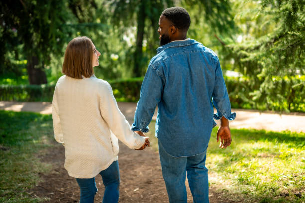 istock Rear view of a multi-ethnic couple walking along a park 2181133785