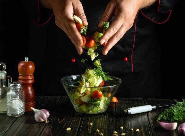 istock Chef preparing vegetable mix for breakfast. Preparing salad with fresh vegetables on kitchen table. The cook hands mixing chopped vegetables in bowl 2181134163