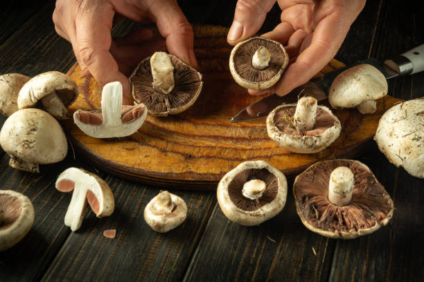 istock Cleaning champignon mushrooms by male hands on kitchen table after picking in forest. Concept of healthy mushroom diet at home 2181134218