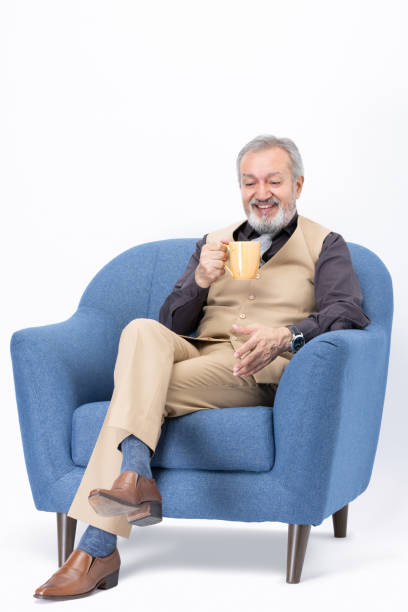 istock Senior man drinking coffee sitting on sofa on white background stock photo 2181137434