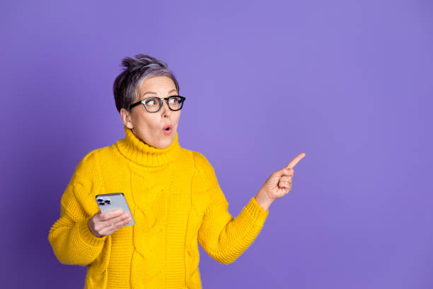 istock Photo of shiny impressed lady dressed yellow pullover chatting modern gadget pointing empty space isolated purple color background 2181139977