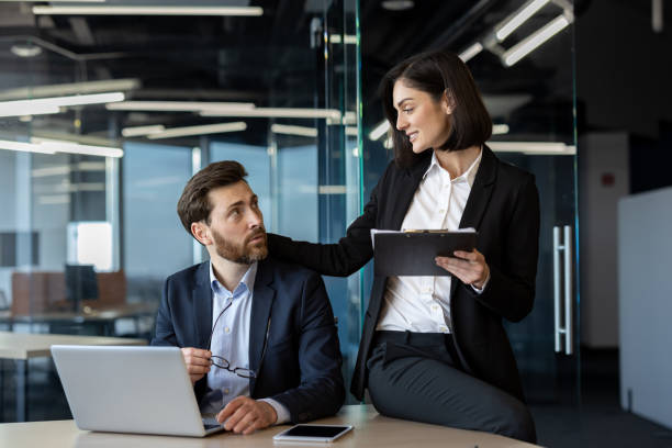 istock Professional colleagues engaging in friendly conversation at an office with modern glass walls and ambient lighting, showcasing teamwork and positive interaction in a corporate environment 2181141365