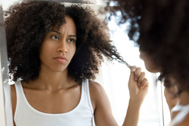 istock Woman pulling her afro hair in front of mirror 2181146063