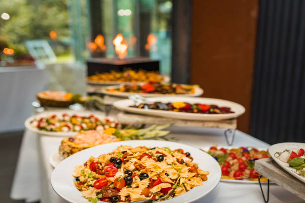 Lifestyle food scene featuring a bowl of pasta salad paired with fresh bread and bamboo cutlery resting on a soft linen napkin. Shot from above on a rustic white wooden background with generous copy space, ideal for themes of casual dining, slow food, and everyday home cooking.