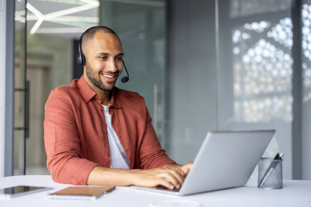 istock Smiling professional wearing headset working on laptop during online meeting in modern office setting 2181150367