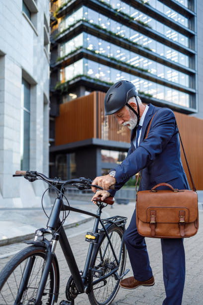 istock Senior businessman with laptop bag and helmet positioning bicycle kickstand while commuting in city 2181154430
