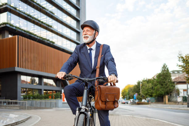 istock Senior businessman in helmet smiling and looking away while commuting on bicycle to work in city 2181154453