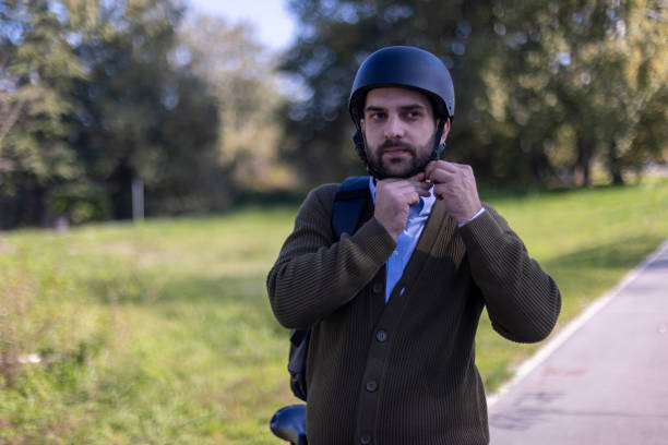 Portrait of a man putting a safety helmet on his head before sitting on his bicycle and continuing his ride to work through the park