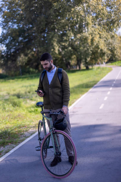 istock A man uses a mobile phone while pushing his bicycle through the park on his way to work 2181155802