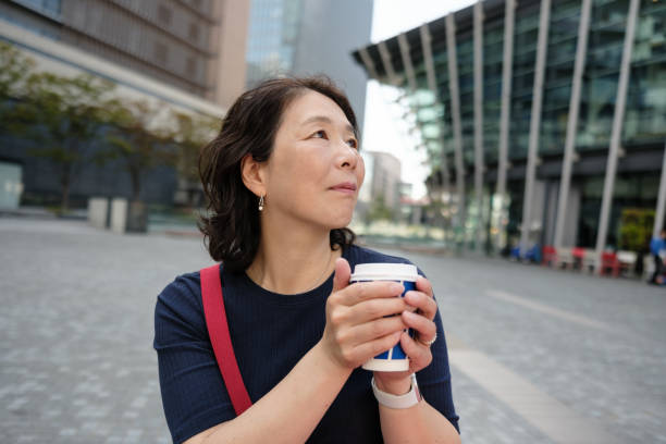 istock Smiling woman holding a coffee cup and looking up 2181159409