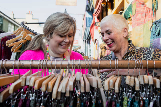 istock Two cheerful friends browsing clothes on a market stall 2181161503