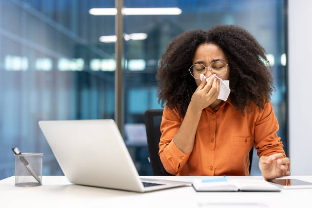 istock Woman sneezing at her desk in an office setting while using a tissue, illustrating common cold symptoms during work hours, health concepts, and the importance of self-care in professional environments. 2181164156