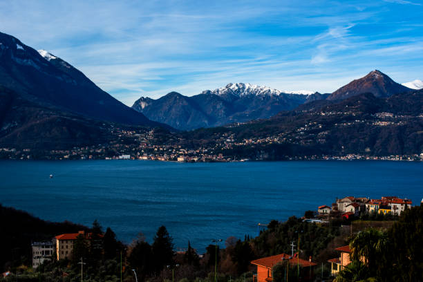 view of Lake Como between high mountains green trees with rocks on the shore and calm autumn waters a spectacular sunset between the peaks of the Alps and Lake Como in Italy