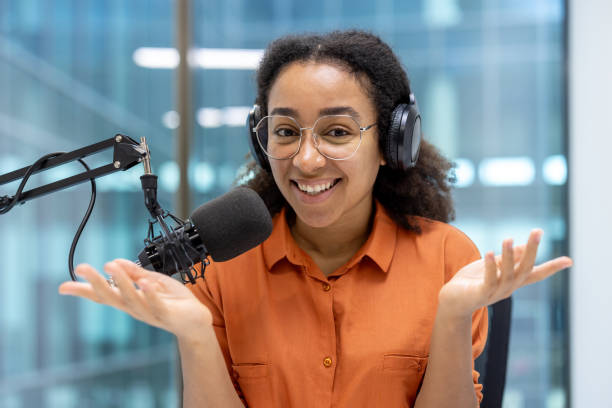 istock Confident podcast host speaking into a microphone with headphones, gesturing with hands. Engaging podcasting environment capturing energy and enthusiasm. Engaged in broadcasting discussion. 2181170126
