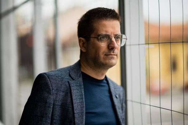 istock Man in glasses looking thoughtfully through wire fence 2181170569