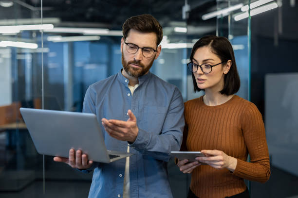 istock Professional coworkers discussing project ideas using laptop and digital tablet in modern office environment 2181172146