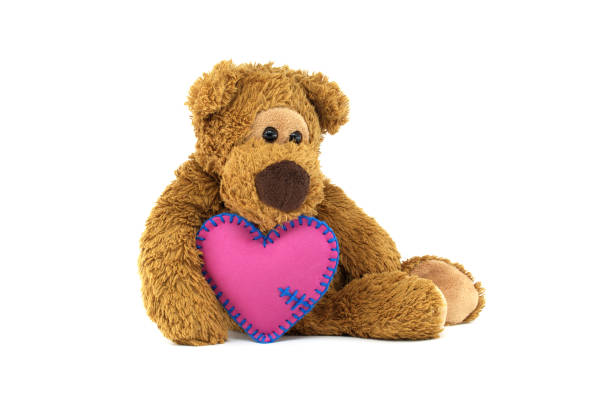 istock Teddy bear holding pink heart with blue stitching, expressing love and warmth on a white background 2181181875