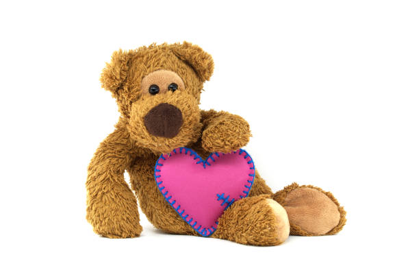 cute teddy bear and red heart shaped toy lying on the beautiful green background
