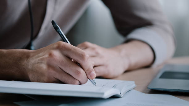 istock Close up unknown right-handed male business man write notes business ideas at organizer writer sit at home office hold pen notice information tasks in dairy making appointments self-education concept 2181183146