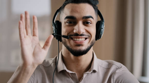 istock Smiling male operator hispanic businessman customer support service assistant representative greeting speak at web camera wear headset with microphone make video conference call remote job interview 2181185418