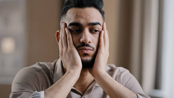 istock Depressed tired hispanic arab man guy businessman worker sit at home feel boredom depression massaging face forehead suffering from insomnia thinking about problem has burnout syndrome lack motivation 2181186382