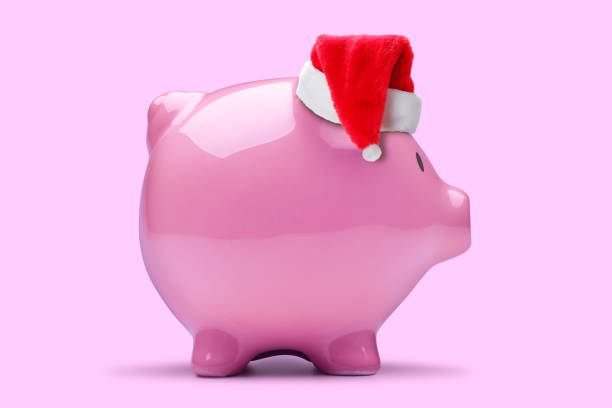 A pink piggy bank wearing a Santa Claus hat isolates on a pink background.