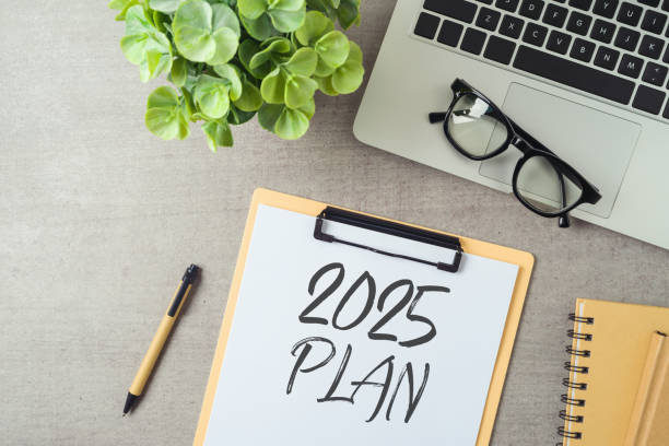 New Year 2025 plan and resolution business concept with notepad, laptop computer and plant on modern office desk. Top view, flat lay