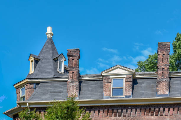 A brick building with a black roof and a chimney. The roof has a turret and the chimney is on the side of the building.