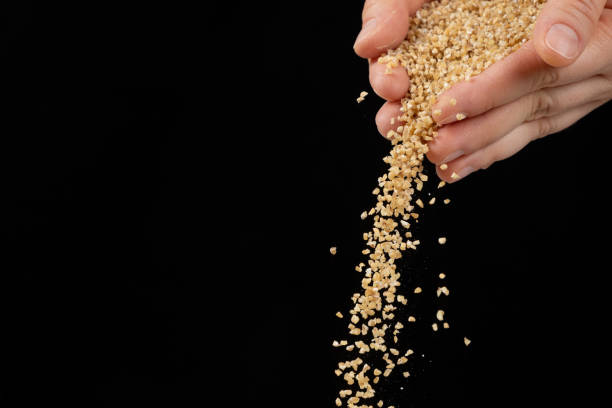 istock Hands pour raw uncooked wheat groats on black background copy space for text 2181209448