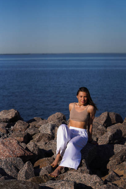 Young brunette woman sitting on rocks overlooking the sea