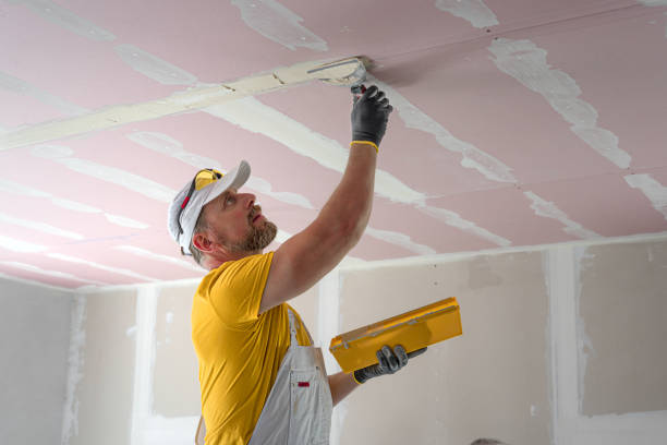 istock The worker make a plasterboard ceiling. He does taping plaster drywall ceiling joints. He is using special drywall taping knife. 2181210369