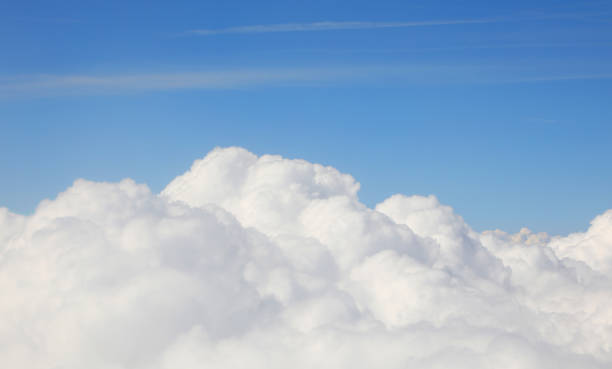 white cumulus clouds below and clear blue sky seen from a passenger airplane during daytime flight