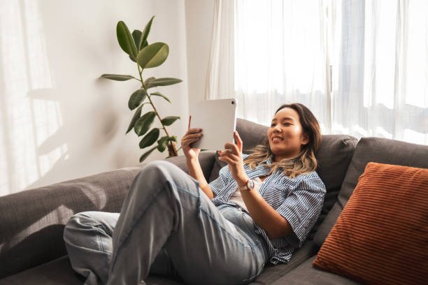 istock Asian woman relaxing on a sofa with a digital tablet 2181212224