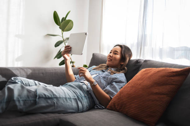 istock Asian woman relaxing on sofa using a digital tablet at home 2181212231