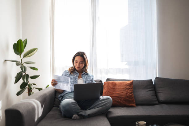 istock Asian woman working on laptop at home with documents 2181212247